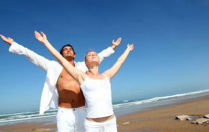 Healthy couple beside the beach doing yoga